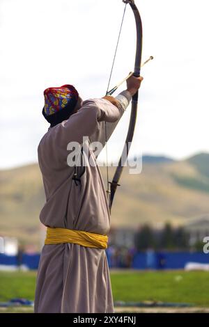 Ulaanbaatar, Mongolei, 11. Juni 2007: Rückansicht eines männlichen Bogenschützen, der eine Bogenschnur zieht, mit dem Ziel, das Naadam Festival Bogenschießen in Asien anzuvisieren Stockfoto