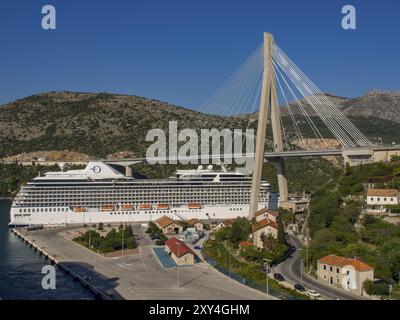 Großes Kreuzfahrtschiff unter einer Seilbrücke vor einer bergigen Landschaft, Dubrovnik, Mittelmeer, Kroatien, Europa Stockfoto