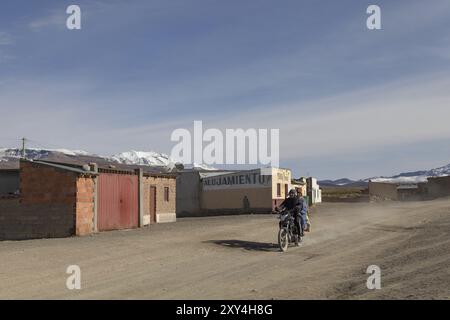 Sajama, Bolivien, 27. Oktober 2015: Bolivianischer Mann und seine Frau fahren mit einem motorrad durch das Dorf in Südamerika Stockfoto