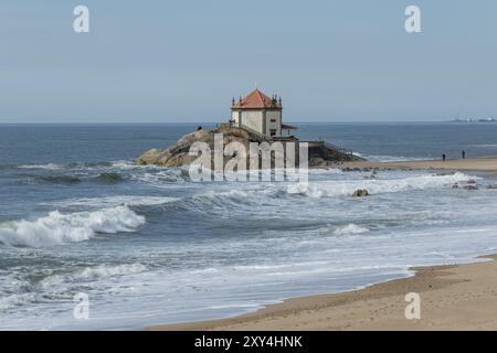 Wellen, Surfen, Sandstrand und Wahrzeichen Capela do Senhor da Pedra, historische Kapelle auf einem Felsen am Praia do Senhor da Pedra, Gulpilhares, Vila Nova de Gaia Stockfoto