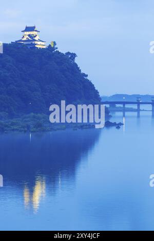 Das ferne Schloss Inuyama wird von Flutlichtern beleuchtet und am Abend vom Fluss Kiso auf einem Waldberg zur blauen Stunde in der Präfektur Gifu, J, reflektiert Stockfoto