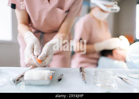 Close-up-Nahaufnahme von nicht erkennbarer Krankenschwester-Assistent, der die Kappe von der Nadel der Spritze entfernt und sich auf die Operation im Krankenhaus vorbereitet. Stockfoto