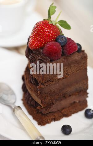 Stück Schokolade Kuchen mit Zuckerguss und frischen Beeren auf hellem Hintergrund Stockfoto