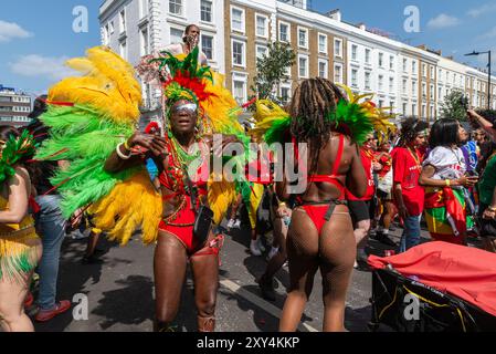 Tanzen Sie Nachtschwärmer in den Menschenmassen, und folgen Sie mobilen DJs bei der Notting Hill Carnival Grand Parade 2024. Erwachsenentag am Montag an Feiertagen. Eigenschaften Stockfoto