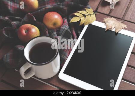 Tablet heißen Tee karierte Decke Äpfel und Blätter im Herbst auf alten hölzernen Hintergrund Vintage tonning Herbst Konzept Mock up Stockfoto