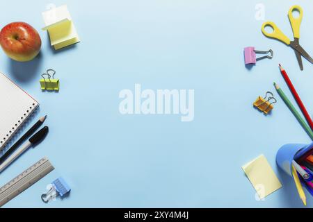 Flat Lay mit Schul-, Arbeits- oder Bildungskonzept mit verschiedenen Schulzubehör, Stiften, Bleistift, Notizblock, Büroklammern, apfel, Lineal, Schere, pape Stockfoto