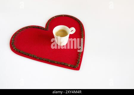 Tasse Kaffee auf rotem Filz Herzen mit Kaffeebohnen um Stockfoto