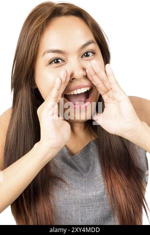 Porträt eines hübschen asiatischen Mädchens, ärmelloses graues Oberteil, hellbraunes Haar, das Geheimnisse erzählt oder eine Ankündigung schreit, die in die Kamera blickt, Hände um Mo herum schröpft Stockfoto