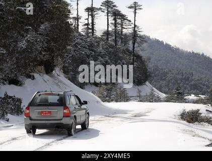 Auto fahren in den Schnee am Thrumshingla-Pass, der Grenze zwischen Mittel- und Osteuropa Bhutan Stockfoto