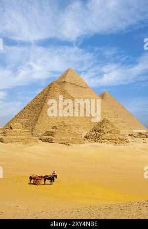 Eine Gruppe von Touristen steigt von ihrem Pferdewagen ab, um alle ägyptischen Pyramiden an einem wolkigen Tag in Gizeh, Kairo, Ägypten, zu sehen. Vertikale Kopie sp Stockfoto