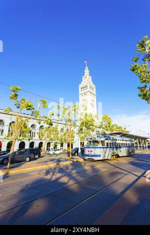 Historisches Ferry Building, das an einem sonnigen Sommertag in San Francisco vor einer grauen Vintage-Straßenbahn des F Market auf Schienen entlang des Embarcadero steht. Stockfoto