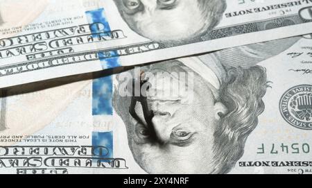 Miniaturfigur Geschäftsmann mit 100-Dollar-Banknote auf dem Hintergrund. Draufsicht Stockfoto