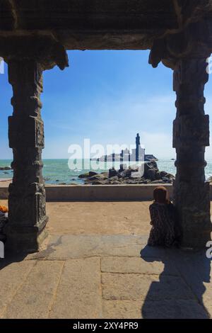 Kanyakumari, Indien, 22. Februar 2015: Indianerin sitzt im 16-beinigen Mandapfelpavillon und sieht die Statue von Thiruvalluvar auf einer Insel vor der Küste. Stockfoto