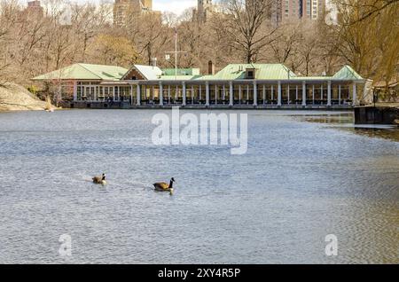 Central Park Boathouse Restaurant, New York City bei winterlichem Tageslicht mit See und zwei Vögeln auf dem Wasser im Vordergrund, horizontal Stockfoto