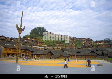 Xijiang, China, 15. September 2007: Dorfbewohner trocknen Mais auf dem Stadtplatz unter den wunderschönen hölzernen Hügelhäusern im Dorf Miao, das eine ethnische Minderheit beherbergt Stockfoto