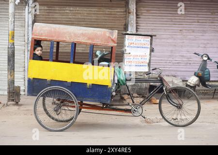 Delhi, Indien, 9. November 2009: Ein junger indischer Schüler reitet zurück auf einer überdachten Rikscha, die dem Schulbus entspricht, und geht in der More zur Schule Stockfoto