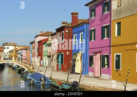 Burano Island, Venedig, Italien, 21. August 2012: Bunte Häuser in einer Reihe auf der Insel Burano in der Lagune von Venedig, Italien. Einige Leute gehen zu Fuß Stockfoto