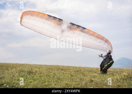 Der Gleitschirmflieger öffnet seinen Fallschirm, bevor er vom Berg im Nordkaukasus abhebt. Füllen Sie den Fallschirmflügel vor dem Start mit Luft Stockfoto