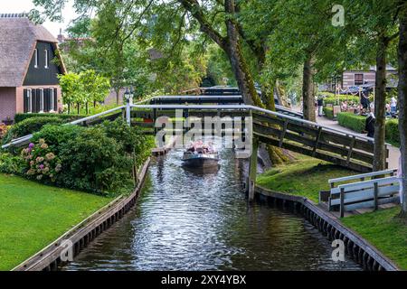 Touristen segeln in einem Elektroboot unter einem hölzernen Steg. Das alte Giethoorn ist ein internationales Touristenziel und zieht jedes Jahr rund 1 Million Touristen in dieses kleine Dorf in der Provinz Overijssel. Foto: ANP / Hollandse Hoogte / Evert Jan Luchies. niederlande aus - belgien aus Stockfoto