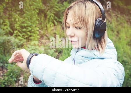 Porträt Junge Fitness-Frau, die ihre Smartwatch ansieht, während sie eine Pause vom Sporttraining macht. Sportsfrau überprüft Puls auf Fitness-Smartwatch d Stockfoto