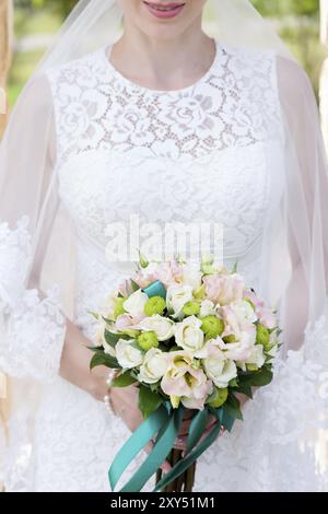 Nahaufnahme eines Brautstraußes in der Nähe der Braut in ihren Armen. Kinnbrust und Blumenstrauß im Rahmen des Hochzeitsglücks. Hochzeitstag Stockfoto