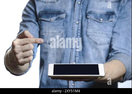 Lässiger Mann in Denim-Hemd, der digitalen Tablet-Computer-Bildschirm in den Händen zeigt. Isoliert auf weiß. Beschneidungspfad für die Anzeige enthalten. Er zeigt mit einem Finger A Stockfoto