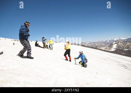 Training zum Korrigieren des Rutschens an Hanglagen oder Gletschern mit Hilfe einer Eispistole. Ein junger Reiseleiter mit Bart erklärt seiner Gruppe, wie man das richtig verlangsamt Stockfoto