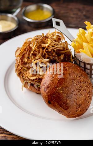 Veganer Burger mit knusprigen Zwiebeln, Saucen und Pommes Frites Stockfoto