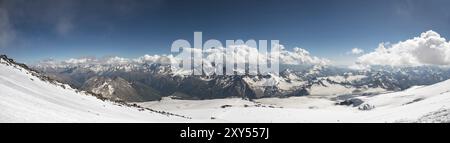 Panorama des kaukasischen Berges mit Wolken, die an den Spitzen von Bergen hängen, die mit Schnee bedeckt sind, fotografiert vom Hang des Vulkans Elbrus Stockfoto