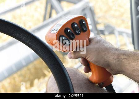 Die Hand des Mannes hält den Steuerhebel des Kornhäckslers neben dem Lenkrad Stockfoto