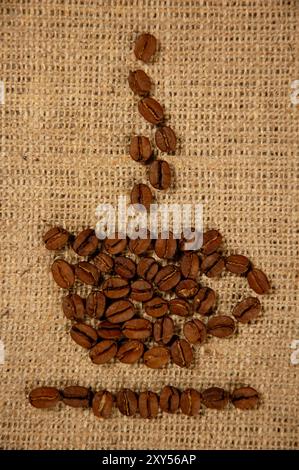 Konzeptuelles künstlerisches Muster einer Tasse Kaffee aus Kaffeebohnen auf einem sackenden Hintergrund Stockfoto