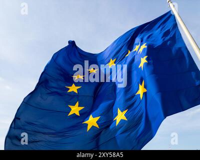 Eine Nahaufnahme der im Wind winkenden Flagge der Europäischen Union mit ihrem berühmten blauen Hintergrund und goldenen Sternen. Durch die Bewegung des Stoffes wird ein zusätzlicher Effekt erzielt Stockfoto