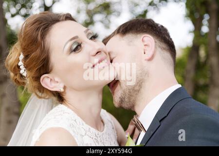 Nahaufnahme eines liebenswerten Paares von frisch vermählten Brautpaaren vor dem Hintergrund von Sommergrün. Das Konzept von Hipsters glücklichem Leben in der Ehe Stockfoto