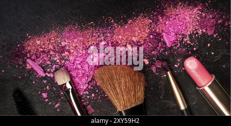 Ein Panorama aus Make-up-Pinseln, Lippenstift und zerquetschter Kosmetik, von oben auf schwarzem Hintergrund mit einem Platz für Logo, ein Schönheitsdesign-templat Stockfoto