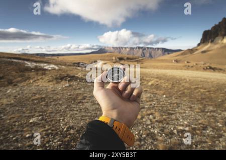 Ein männlicher Wanderer sucht im Herbst eine Richtung mit einem magnetischen Kompass in den Bergen. POV-Aufnahme. Die Hand eines Mannes mit einem Uhrenarmband Stockfoto