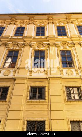 Österreich, 20.01.2019: Blick auf das Gebäude mit gelber Fassade mit dekorativen Fensterrahmen in der Nähe von Treppen, die über den Hügel führen. Touristenziel, Europa Stockfoto