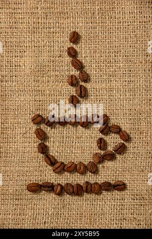 Konzeptuelles künstlerisches Muster einer Tasse Kaffee aus Kaffeebohnen auf einem sackenden Hintergrund Stockfoto