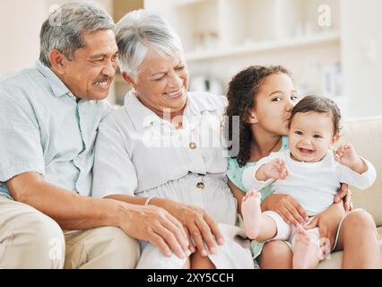 Liebes, Sofa und Großeltern mit Baby und Kind zu Hause für Bindungen, Verbindung oder Familie. Lächeln, glücklicher und älterer Mann und Frau, die ein Kind mit sich hält Stockfoto