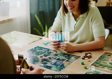 Fröhliche Frau, Die Mit Ihrem Freund Tabletop Game Spielt Stockfoto