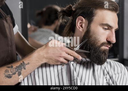 Nahaufnahme Friseur schneiden männlichen Kunden s Bart Stockfoto