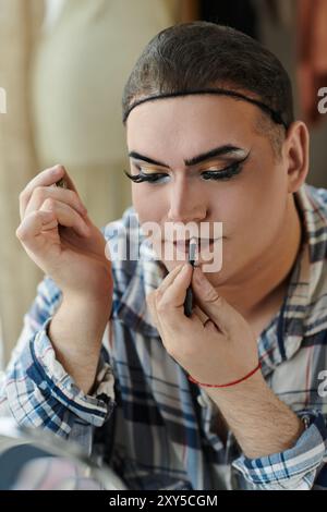 Eine queere Person trägt Lippenstifte und trägt dabei stilvolle Kleidung. Stockfoto