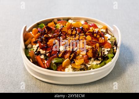 Köstlicher Salat in einer weißen Salatschüssel mit Mandarinen, Feta, Pilzen und Basilikumsauce Stockfoto