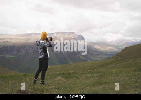 Ein junges Mädchen fotografiert an einem bewölkten Tag ein Plateau auf einem hohen Berg. Blick auf das Mädchen dahinter Stockfoto