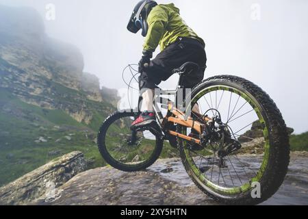 Beine des Radfahrers und Hinterrad Nahaufnahme des hinteren MTB-Bikes in den Bergen vor dem Hintergrund von Felsen bei nebeliger Witterung. Das Konzept der extremen spor Stockfoto