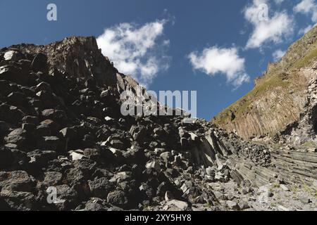 Weitwinkelansicht eines felsigen Abhangs an einem sonnigen Sommertag. Strukturelle sechseckige Klippen im Nordkaukasus Stockfoto