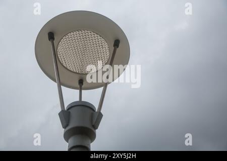 Moderner Lichtmast. Eine vertikale Aufnahme einer metallischen Straßenlaterne gegen den bewölkten blauen Himmel. led-Laterne auf blauem Himmel Hintergrund, Seitenansicht Stockfoto