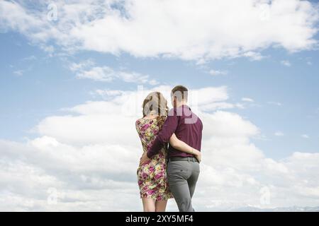 Blick von der Rückseite eines jungen Paares steht in einer Umarmung und blickt in die Ferne gegen den Himmel mit Wolken. Eine Vision für die Zukunft Stockfoto