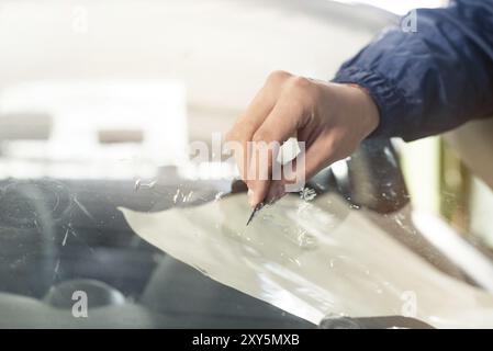 Nahaufnahme Auto Glasierer Arbeiter Befestigung und Reparatur Windschutzscheibe oder Windschutzscheibe eines Autos in Auto-Service-Station Garage Stockfoto