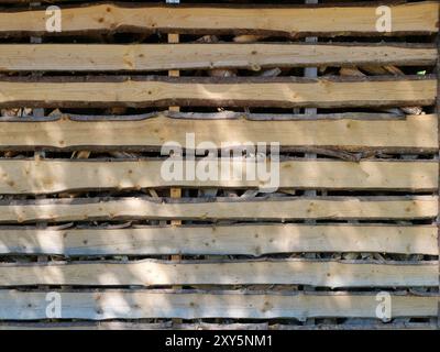 Ein luftiger Holzschuppen zur Lagerung von gespaltenem Brennholz, der aus Lamellen mit großen Spalten gebaut wurde, um das Holz trocken und gut belüftet zu halten. Stockfoto