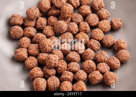 Graue Küchenschüssel mit trockenen Schokoladen-Maiskugeln zum Kochen gesunder Morgenfrühstück Nahaufnahme. Draufsicht Stockfoto